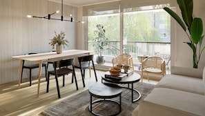 A modern living space with a dining area, a sofa, and a large window with a view of greenery. - Edificio Status Santiago by Domus Travels (Santiago)