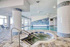 Une piscine intérieure dotée d’un jacuzzi, de murs carrelés et d’un sol en briques.