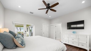 A bedroom with a bed, a ceiling fan, a TV, and a dresser. - Emerald Palms Waterfront Pool Dock Games (Marathon)