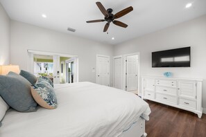 Ein Schlafzimmer mit einem Bett, einem Deckenventilator, einem Fernseher und einer Kommode.
