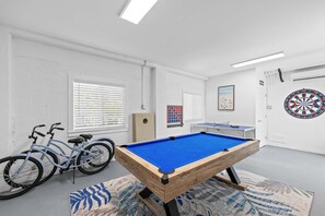 A room with a pool table, bicycles, and a dartboard. - Emerald Palms Waterfront Pool Dock Games (Marathon)