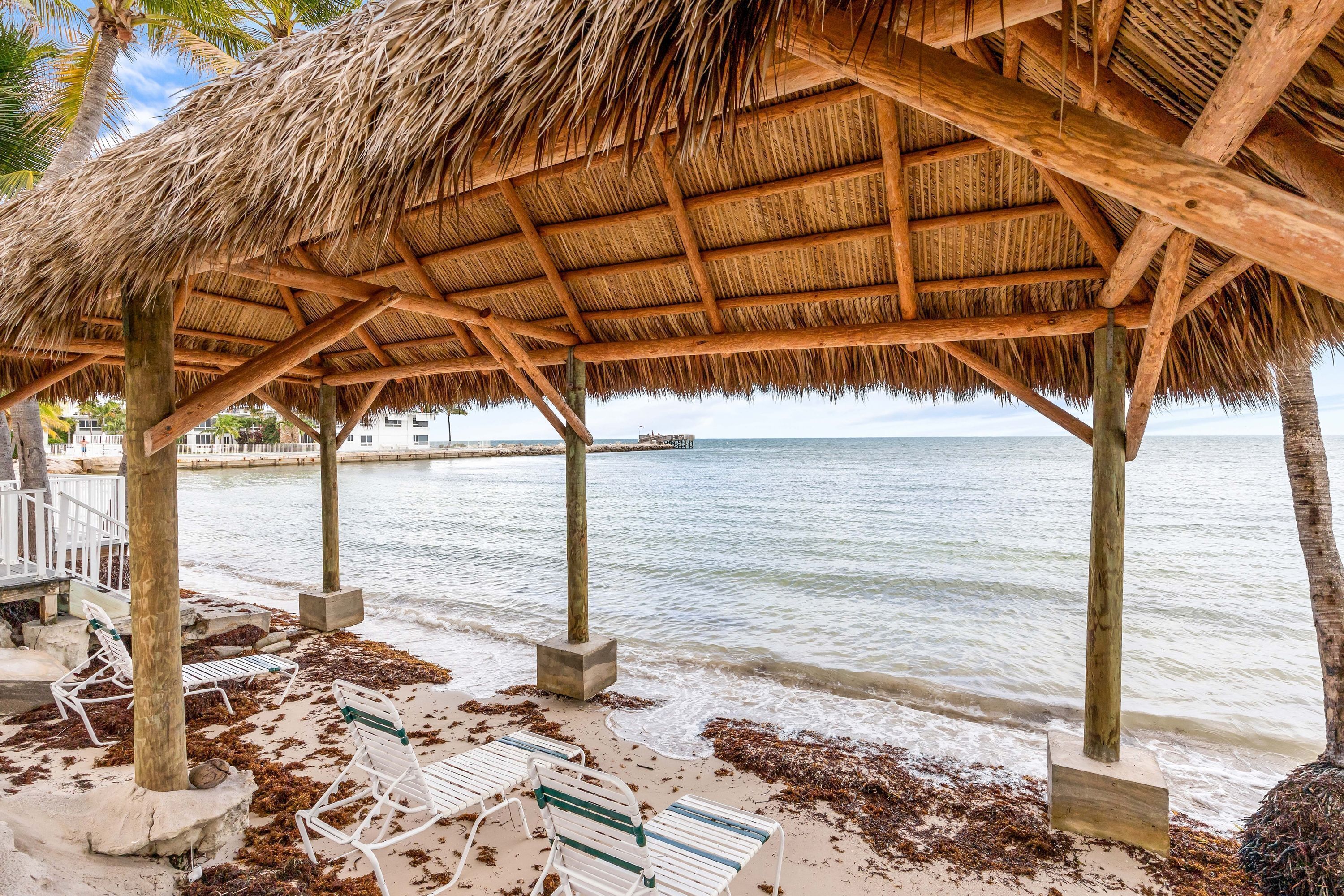 A beachside structure with a thatched roof, wooden beams, and concrete supports.