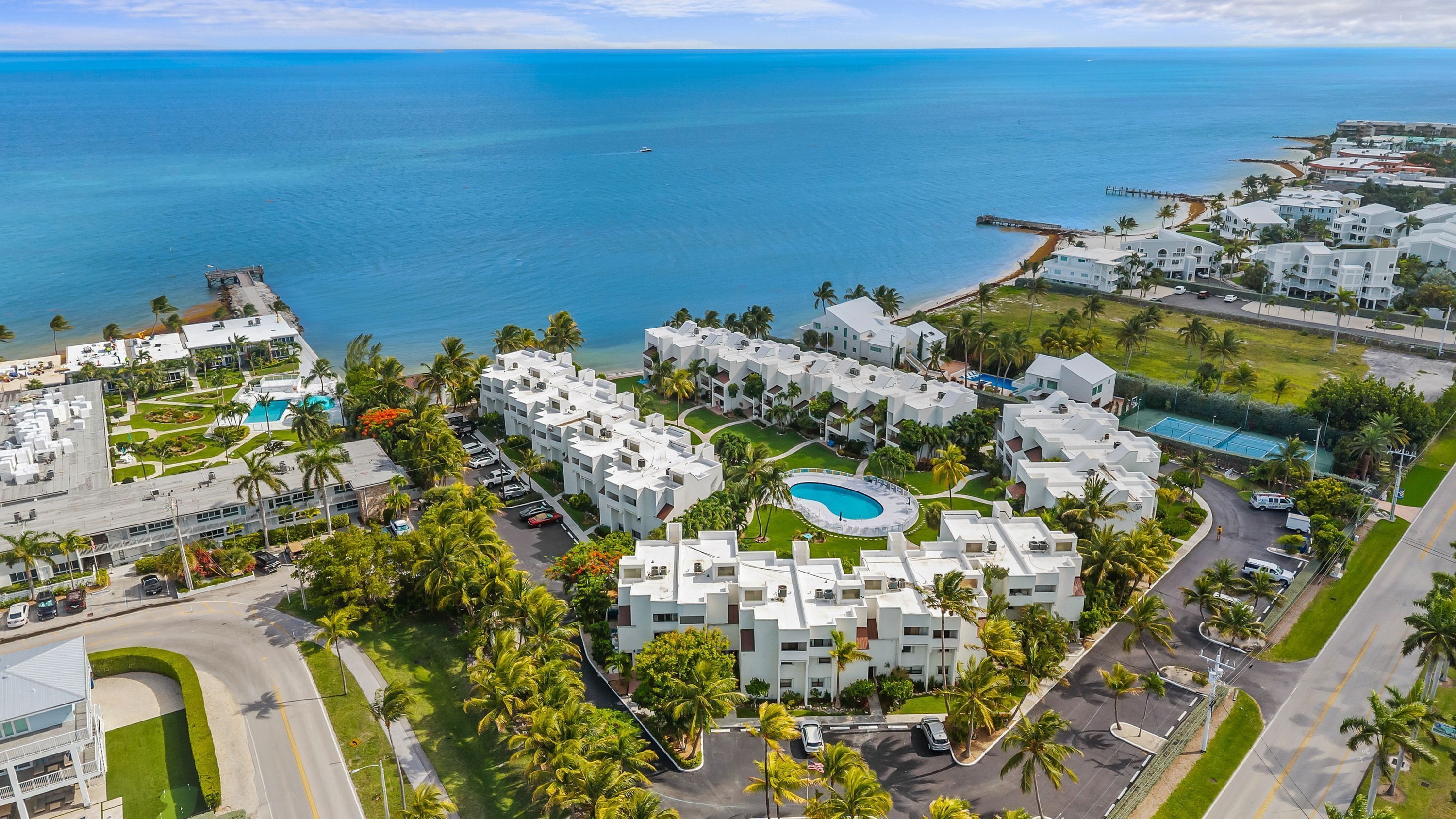 Un resort con varias edificaciones blancas, una piscina y vistas al océano.