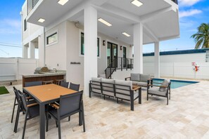 A covered outdoor area with a pool, a dining table with chairs, and a sofa. - Cielo del Mar - Waterfront - Heated Pool - Dock (Marathon)