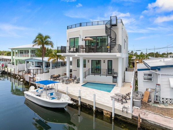 A modern multi-story house with a pool, docked boat, and outdoor seating area. - Cielo del Mar - Waterfront - Heated Pool - Dock (Marathon)