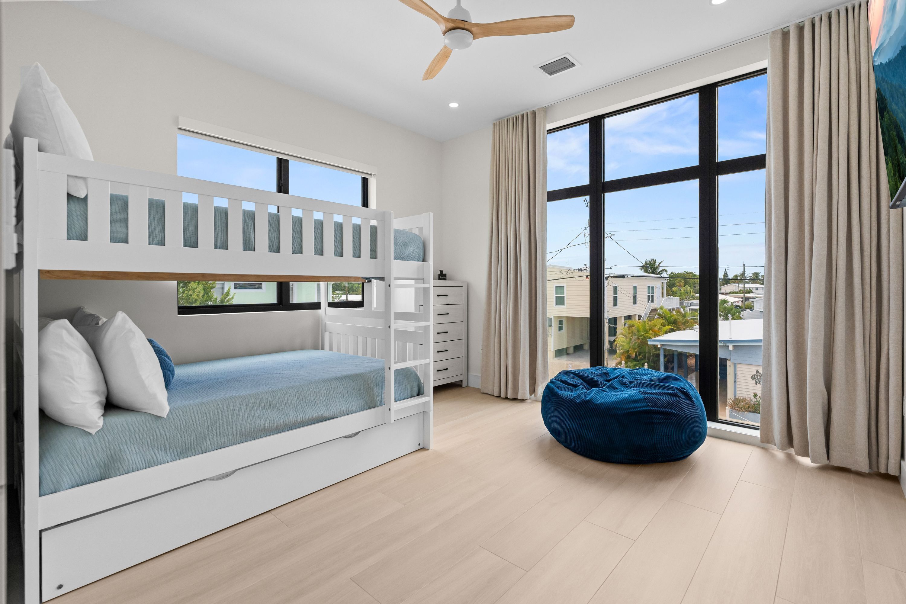 Quarto com beliches e vista para edifícios através de grandes janelas.