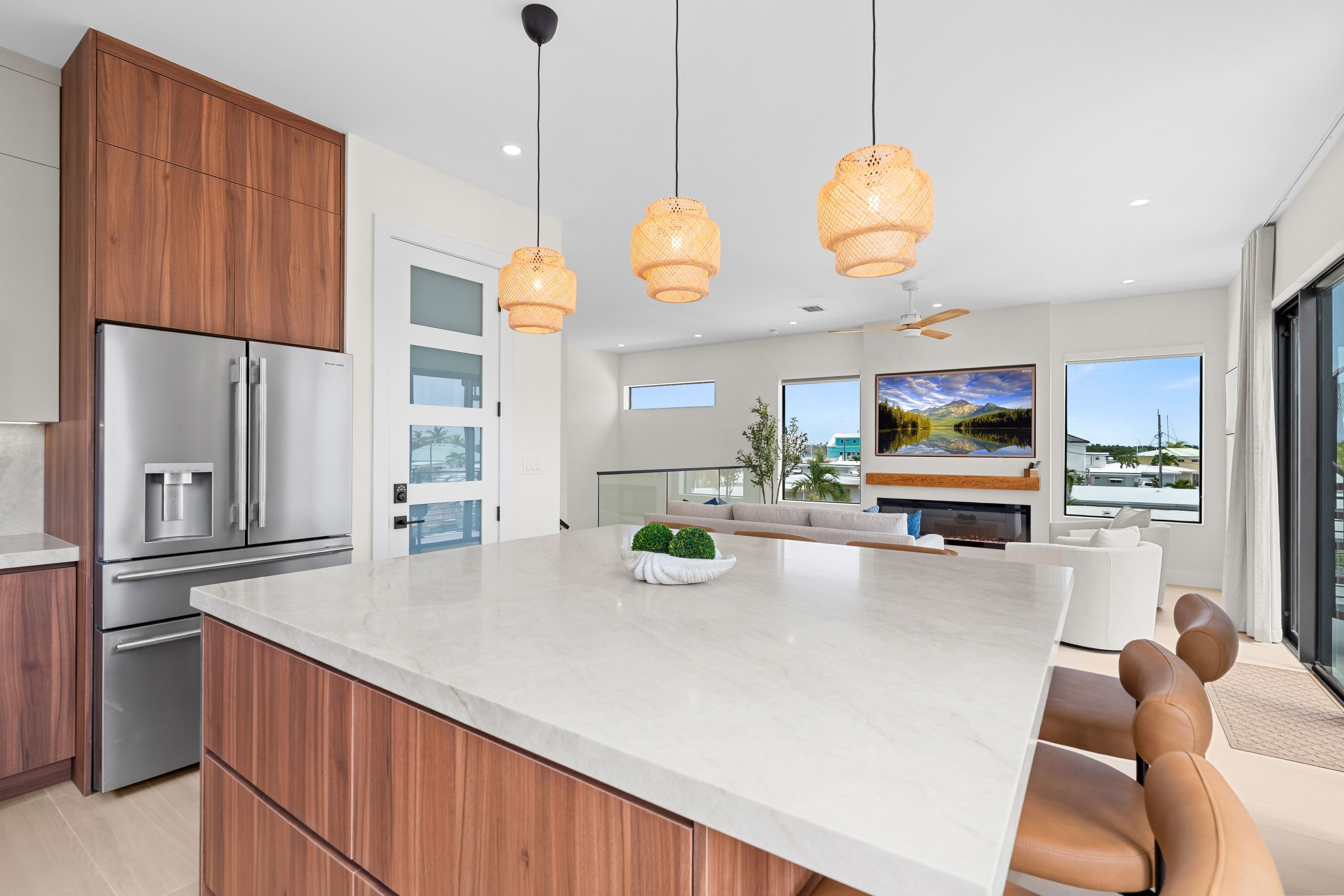 A modern kitchen with a large island, stainless steel appliances, and a dining area with a fireplace.