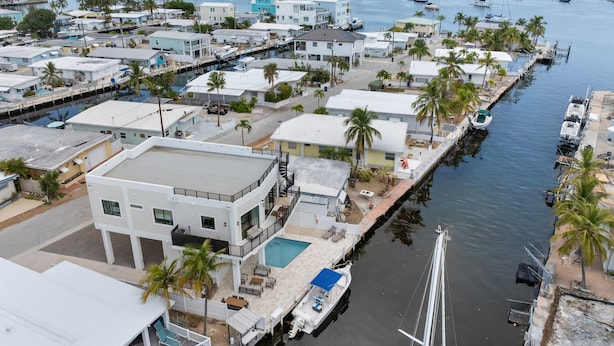 A marina with multiple boats, a swimming pool, and residential buildings. - Cielo del Mar - Waterfront - Heated Pool - Dock (Marathon)