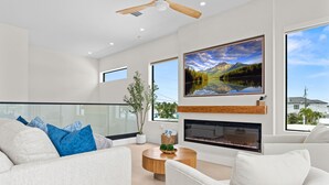 A modern living room with a fireplace, a large window with a mountain view, and a ceiling fan. - Cielo del Mar - Waterfront - Heated Pool - Dock (Marathon)