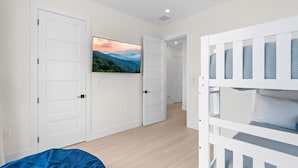 A room with a bunk bed, a television on the wall, and a door leading to another room. - Cielo del Mar - Waterfront - Heated Pool - Dock (Marathon)