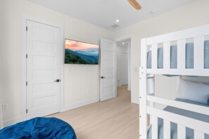 A room with a bunk bed, a television on the wall, and a door leading to another room. - Cielo del Mar - Waterfront - Heated Pool - Dock (Marathon)