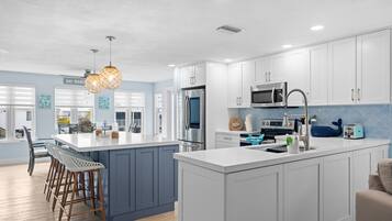 A modern kitchen with white cabinets, stainless steel appliances, and a central island.