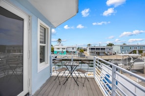 A balcony with a table and chairs, overlooking a marina with boats and houses. - Catch of the Bay - Waterfront - Pool - 35 Dock (Marathon)
