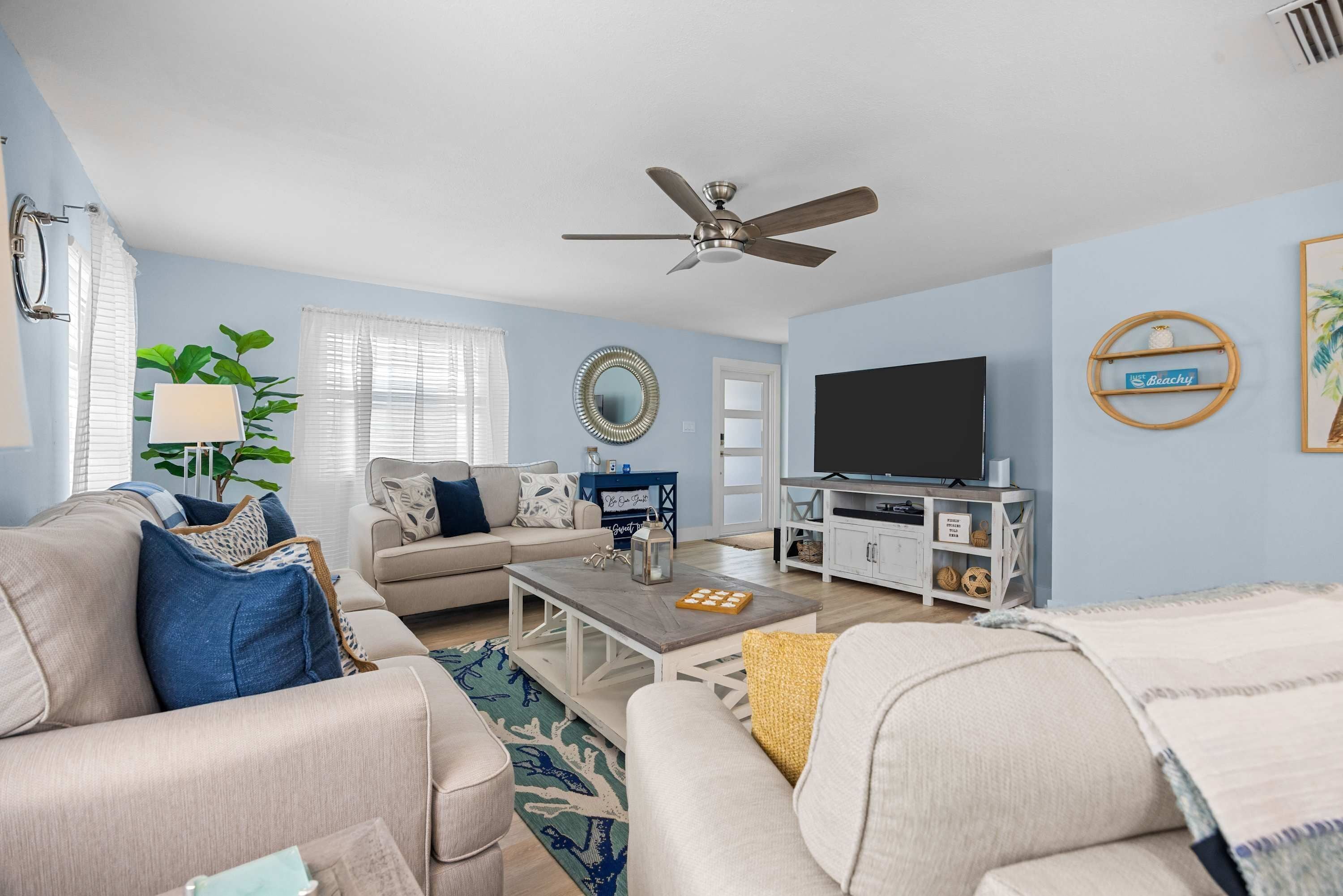 A living room with a sofa, coffee table, TV, and a ceiling fan.