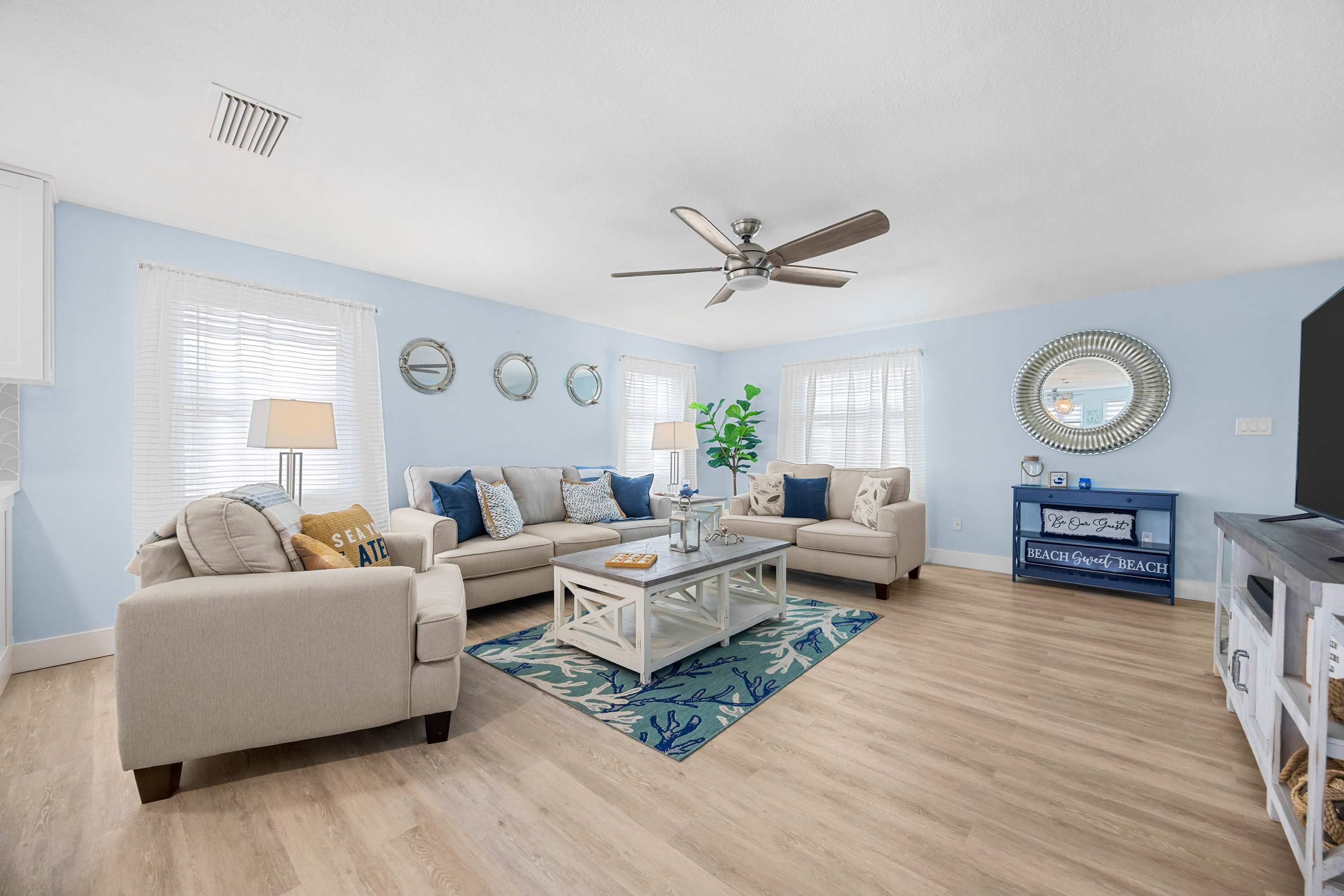 A living room with two sofas, a coffee table, a TV stand, and a ceiling fan.