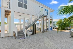 Ein zweigeschossiges Haus mit überdachter Veranda, einer Treppe und einem Schotterweg.