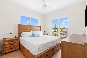 A bedroom with a bed, nightstands, a desk, and a view of the outside. - The Salty Coconut Waterfront Dock Hot Tub (Marathon)
