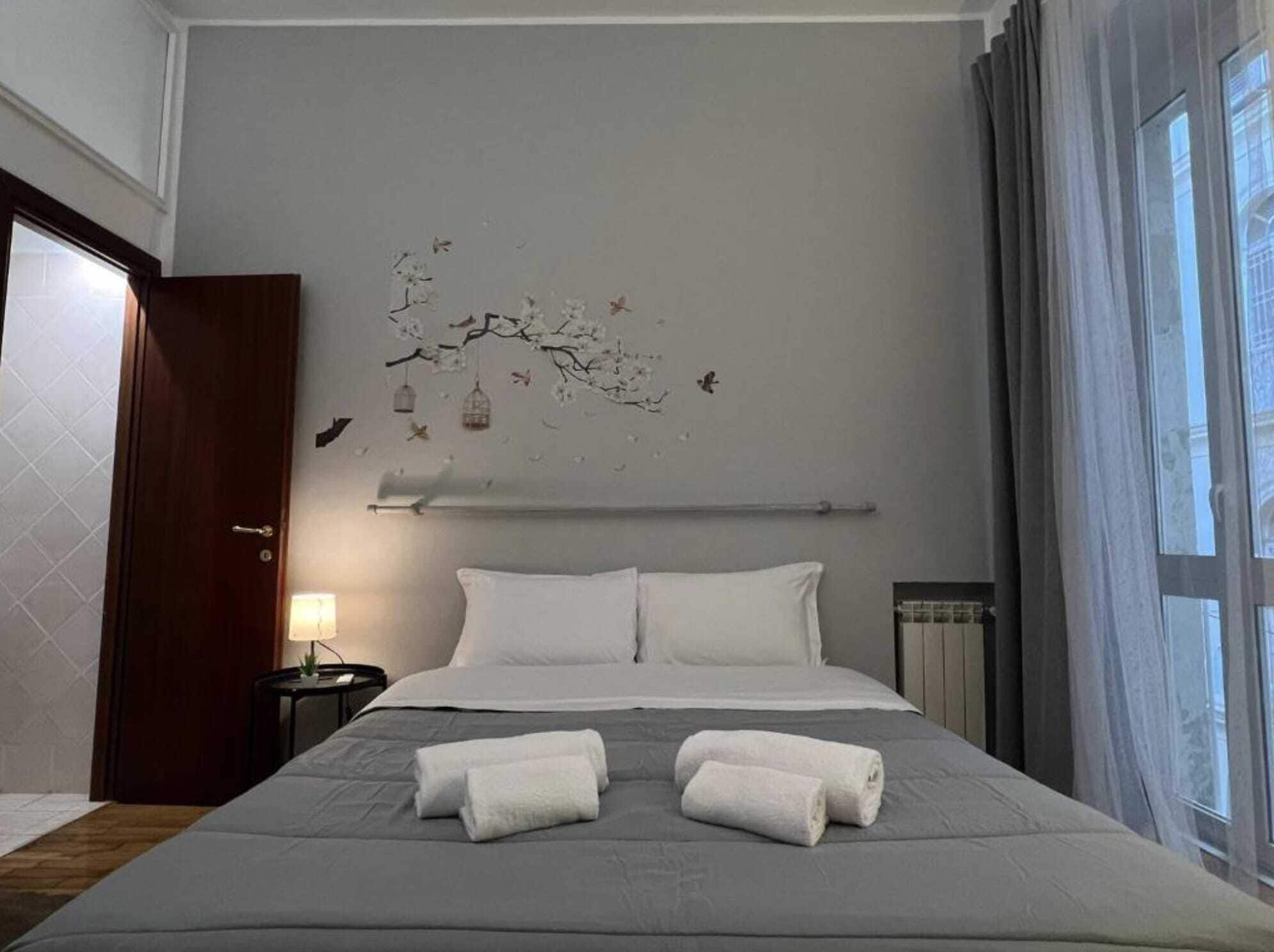 Una camera d'albergo con un letto grande, due cuscini, un comodino con una lampada e una decorazione a parete.