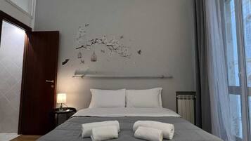 Una camera d'albergo con un letto grande, due cuscini, un comodino con una lampada e una decorazione a parete.