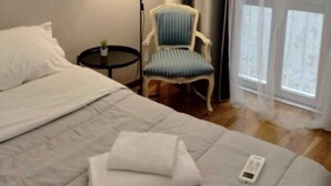 A hotel room with a bed, a chair, a lamp, and a window.