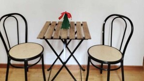A small wooden table with a Christmas tree decoration, flanked by two chairs with woven seats.