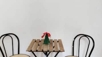 Un piccolo tavolo di legno con un'addobbo natalizio, affiancato da due sedie con sedili in vimini.