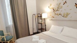 A hotel room with a bed, a chair, a nightstand, and a wall decoration.