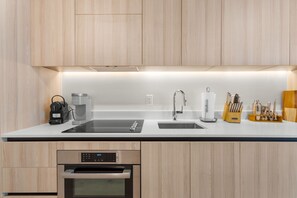 Une cuisine moderne équipée d’un four encastré, d’une machine à café et d’un bloc à couteaux.