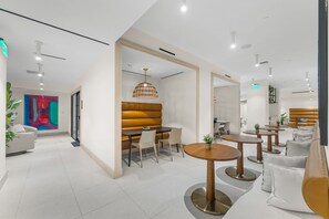 Ein modernes Interieur mit einer Sitzecke, Tischen und einem farbenfrohen abstrakten Gemälde.