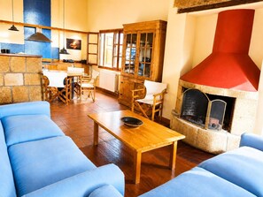 A cozy living room with a fireplace, wooden furniture, and a stone wall. - Stone House Central Filiatra - 7min From the Beach (Trifylia)
