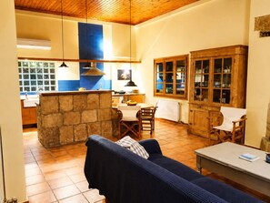 A cozy living area with a stone fireplace, wooden furniture, and a dining table. - Stone House Central Filiatra - 7min From the Beach (Trifylia)