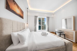 Ein modernes Hotelzimmer mit einem großen Bett, einem Schreibtisch, einem Stuhl und einem großen Fenster mit Vorhängen.