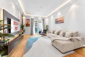 Ein modernes Wohnzimmer mit einer Couch, einem Fernseher und Blick auf die Stadt durch das Fenster.