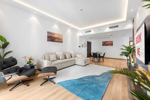 Ein modernes Wohnzimmer mit einer Eckcouch, einem Essbereich und einem großen Gemälde an der Wand.