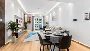A modern dining area with a round table, chairs, and a view of the cityscape through a glass door. - Stayshort - Modern 2BR Apartment in Sulafa Tower Dubai Marina Near to Beach JBR - Sleeps 6 (Dubai)