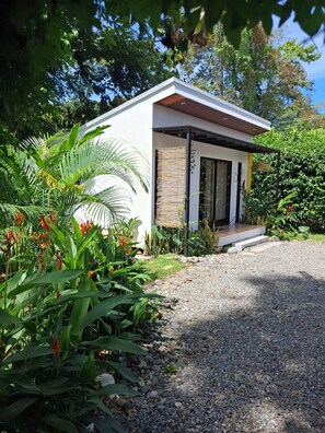 A modern house with a gravel driveway and lush greenery. - Casita Ola Negra, just minutes from the beach—a cozy private studio for 2 people (Puerto Viejo de Talamanca)