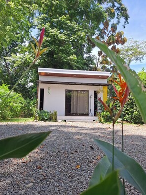 A modern building with a flat roof, large windows, and a gravel driveway. - Casita Ola Negra, just minutes from the beach—a cozy private studio for 2 people (Puerto Viejo de Talamanca)