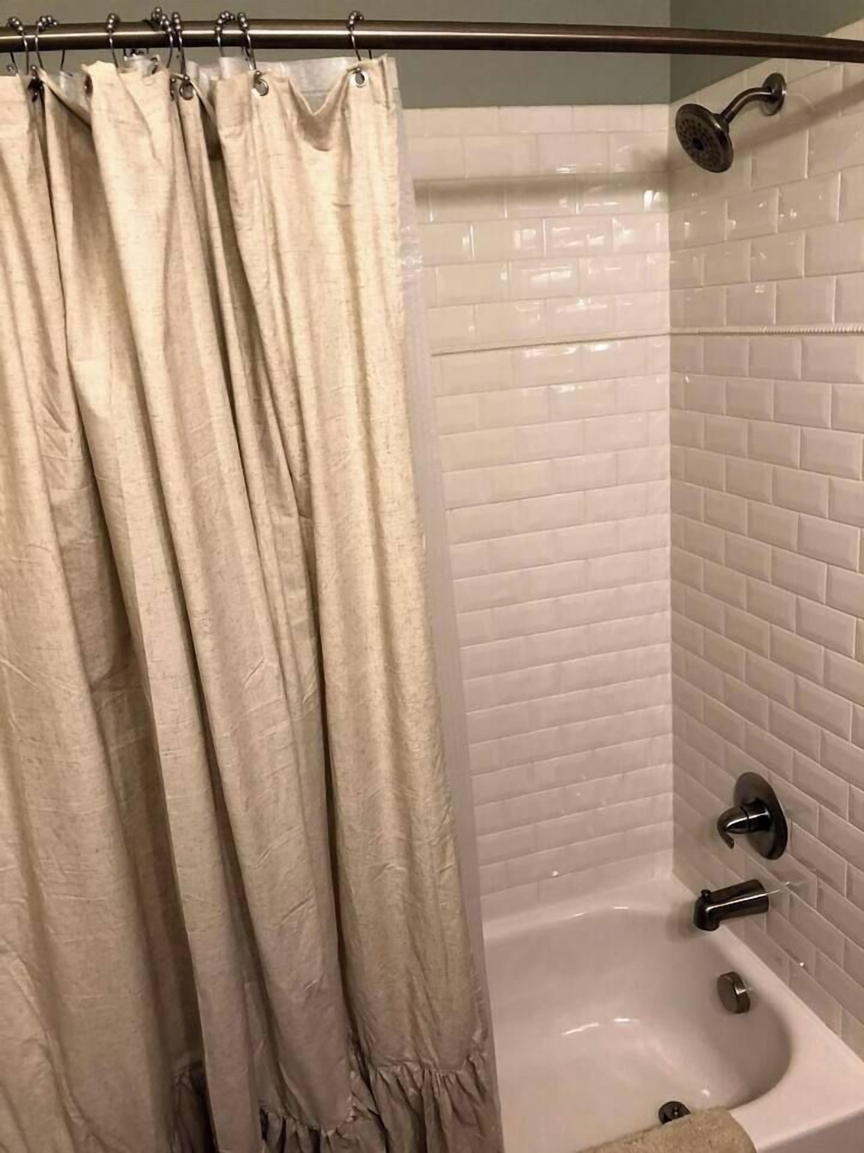 A bathroom with a bathtub, a showerhead, and a curtain.