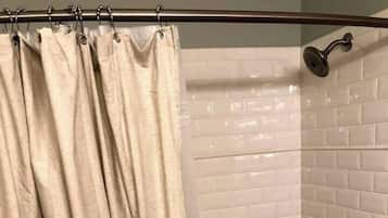 A bathroom with a bathtub, a showerhead, and a curtain.