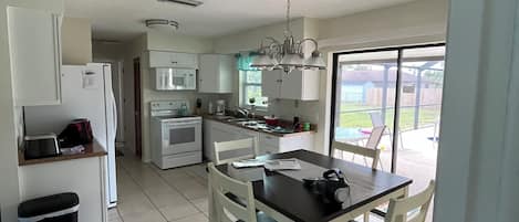 Una cocina con armarios blancos, una mesa de comedor con sillas y vistas al exterior.