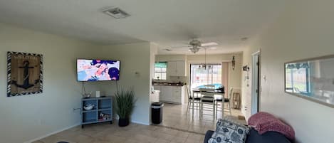 A living room with a sofa, TV, and a view into the kitchen.