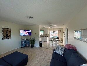 A living room with a sofa, TV, and a view into the kitchen. - Winds And Waves 
Delightful 2-bedroom house in Englewood for your getaway (Englewood)