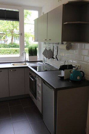Eine moderne Küche mit eingebautem Geschirrspüler, einem Spülbecken und einem Fenster mit Jalousien.