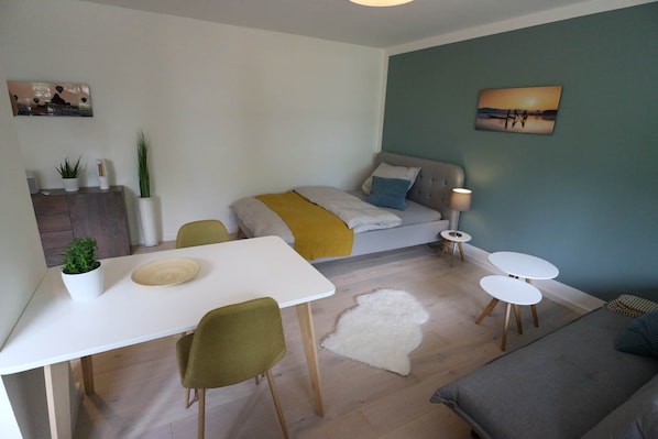 Ein modernes Wohnzimmer mit einer Couch, einem Esstisch und einem kleinen Couchtisch.