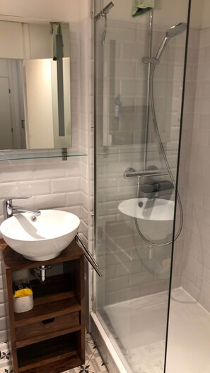 A bathroom with a glass-enclosed shower, a white sink, and a mirror above the sink. - Stylish apartment in Munich right next to Südpark (München)