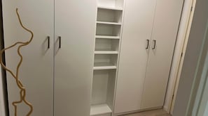 Ein begehbarer Kleiderschrank mit mehreren Regalen und Türen.