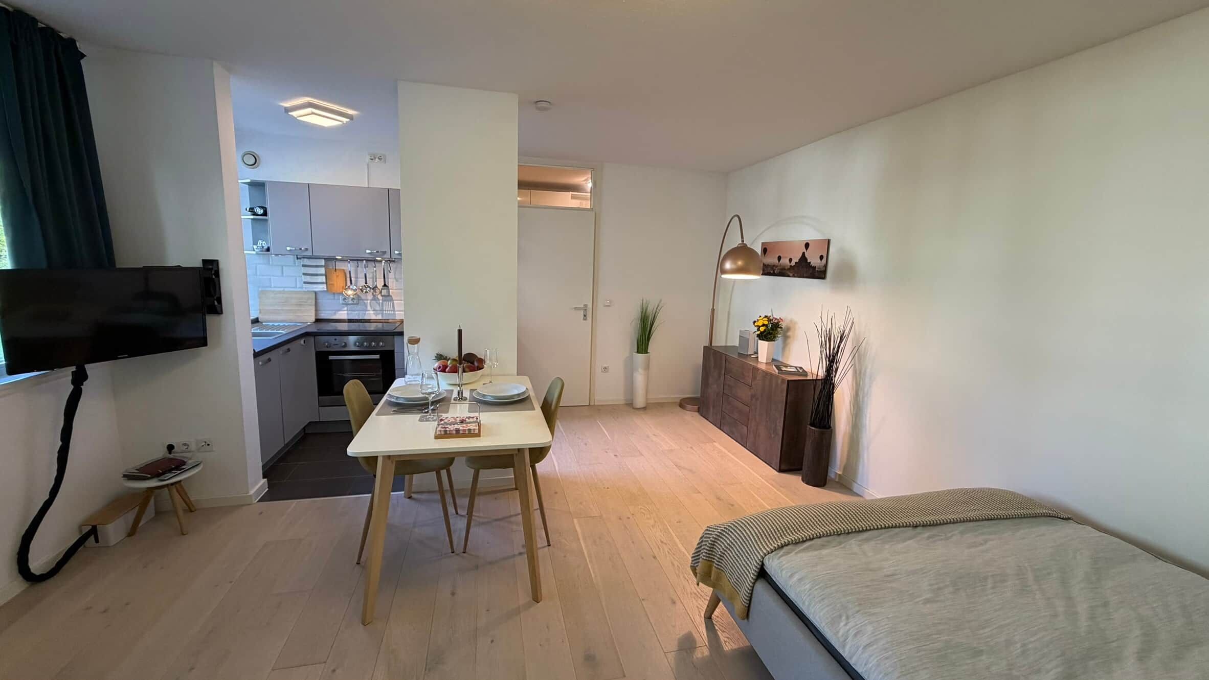 A compact living space with a dining area, kitchenette, and a bed.