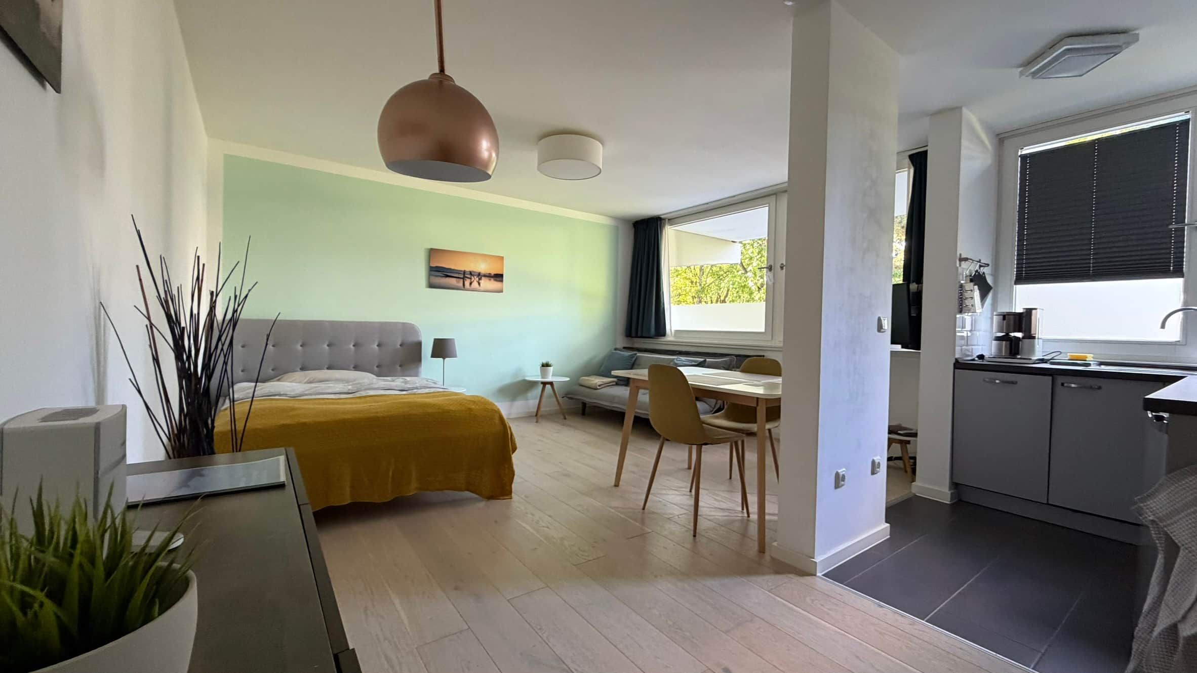 A modern bedroom with a bed, bedside table, and a hanging light fixture.