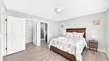 A bedroom with a wooden bed, a nightstand, a bedside lamp, and a closet with open doors.