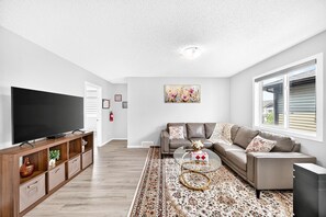 Un salon moderne avec un téléviseur à écran plat, un canapé, une table basse et un tapis à motifs.